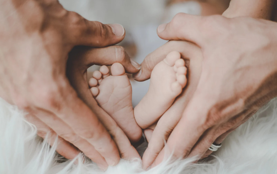 赤ちゃんの足を包み込む、両親の両手